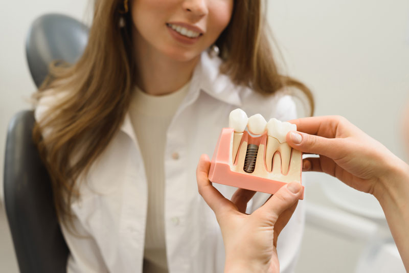 Dental Patient Being Shown A Dental Implant Model